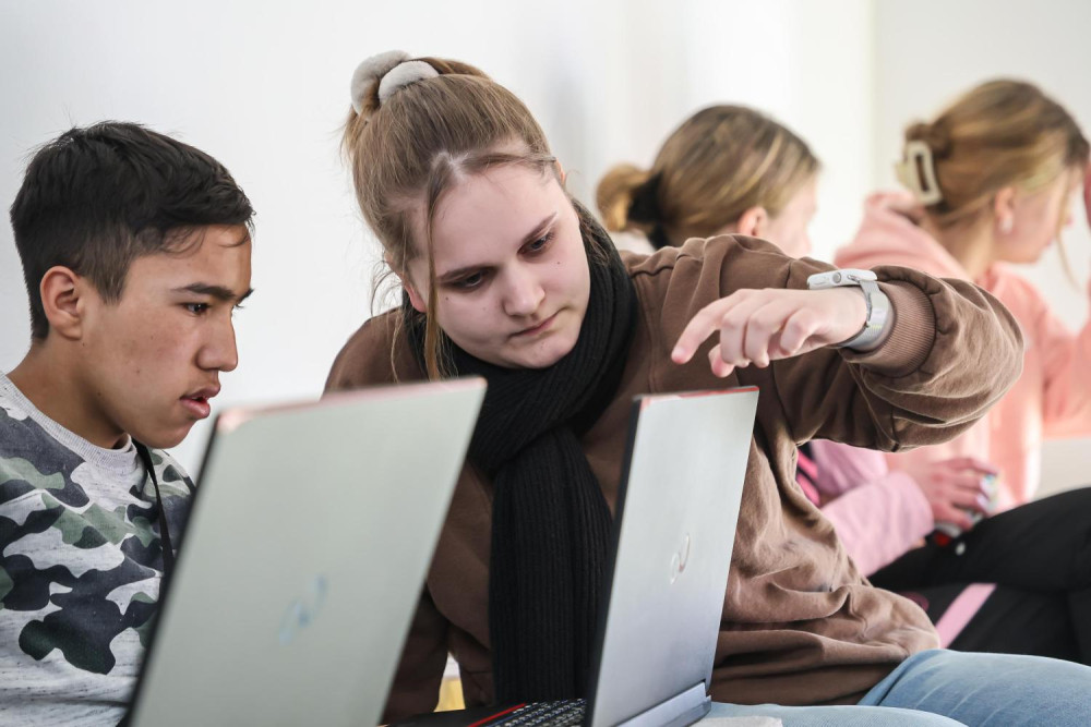 Eine Frau und ein Junge schauen gemeinsam auf den Bildschirm eines Laptops.