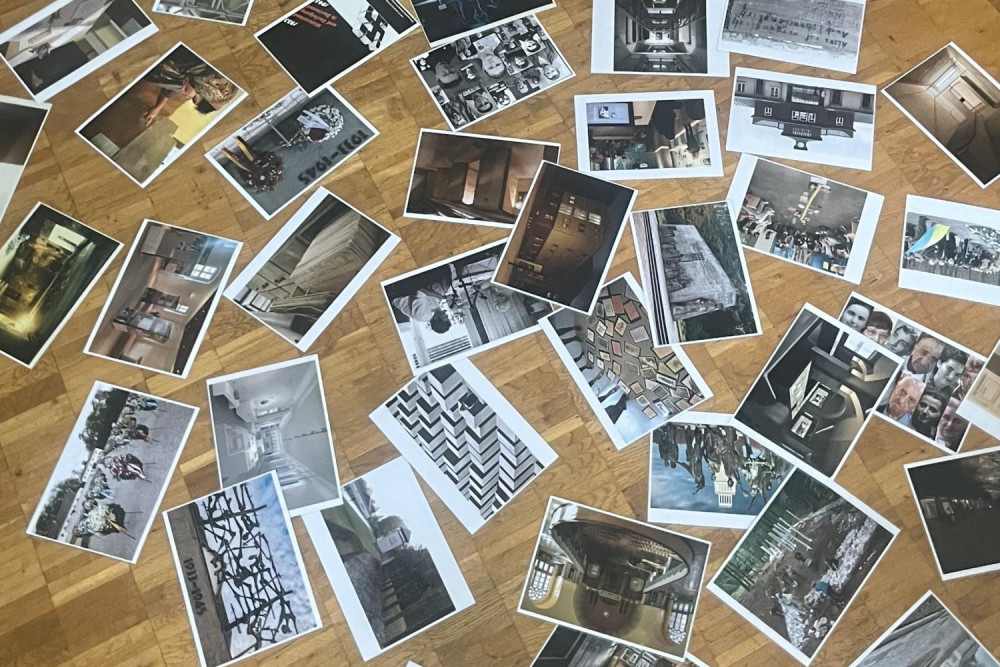 Auf einem Parkettboden sind viele Fotos ausgelegt.