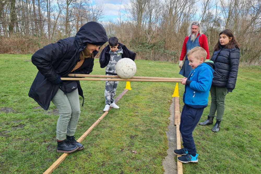 Kinder und Erwachsene beim Ballspiel auf einer Wiese.