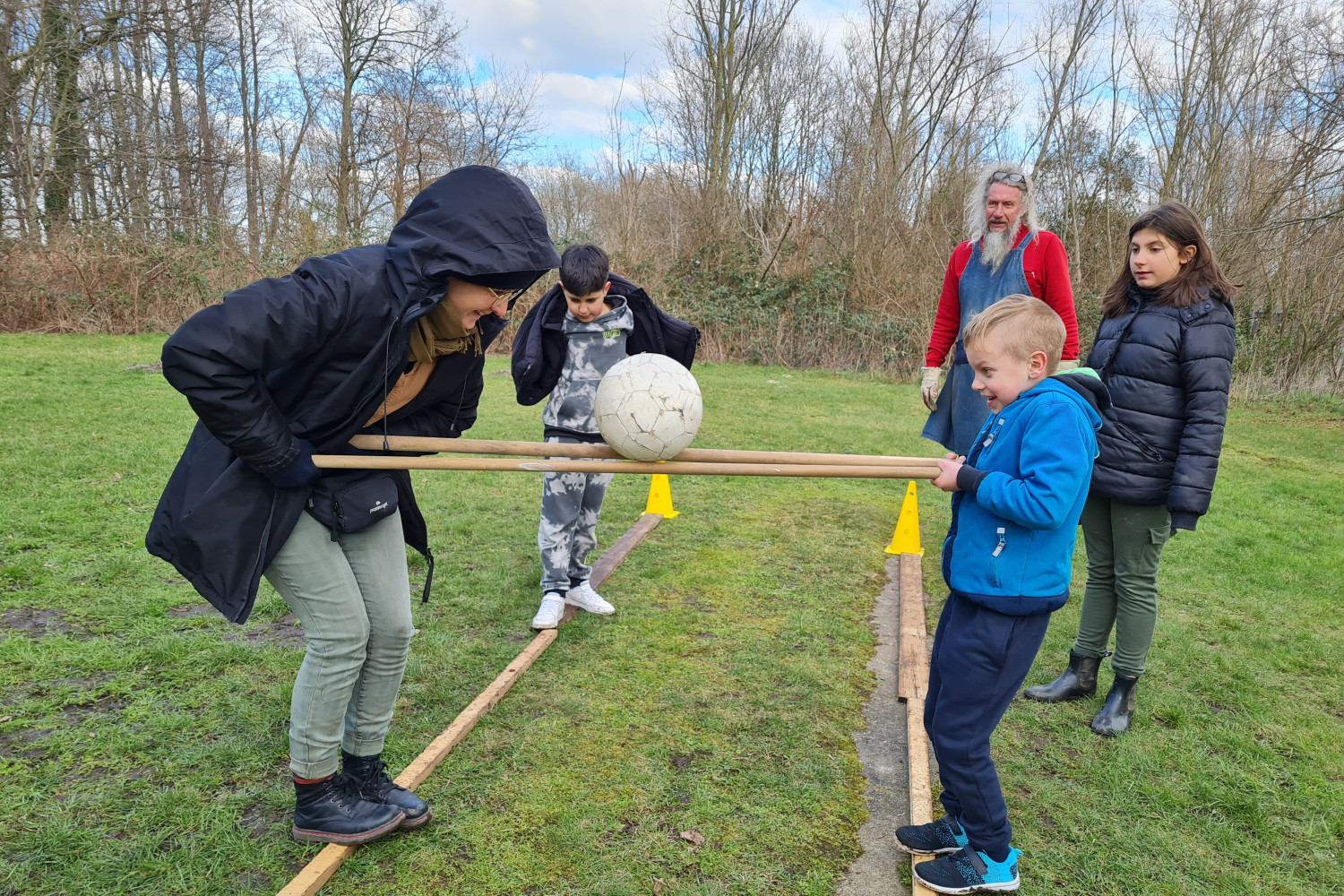 Kinder und Erwachsene beim Ballspiel auf einer Wiese.