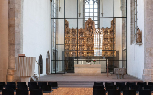 Der goldene Klappaltar mit biblischen Szenen im Altarraum der St. Petri Kirche. Der Altar befindet sich hinter einer Glaswand. Im Altarraum ist ein steinernen Taufbecken, davor einer steinerne Kanzel. Der gesamte Altarraum ist durch die hohen Fenster zu allen Seiten sehr hell.